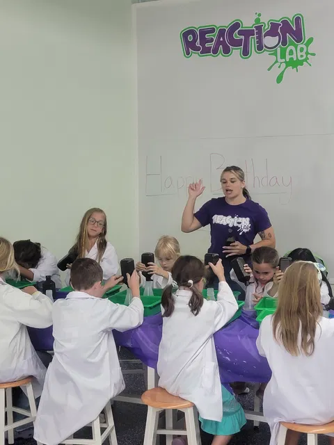 Group of kids in lab coats doing science activities at Reaction Lab