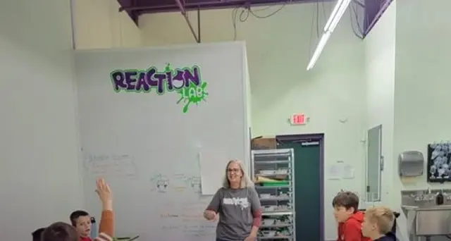 Instructor leading a small-group science session at Reaction Lab