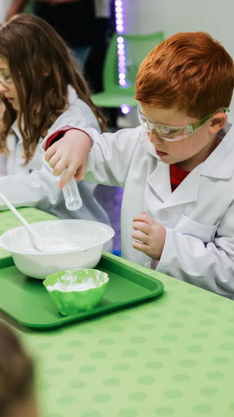 Child in lab coat doing hands-on science experiment at Open Lab