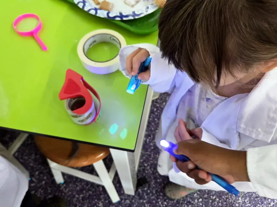 Kids examining evidence under UV light at Reaction Lab